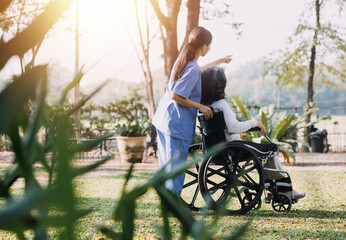 Asian young caregiver nurse support senior older male walking outdoors. Specialist girl doctor help and take care of elderly mature man patient doing physical therapy in public park at nursing home. - Powered by Adobe