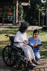 Asian young caregiver nurse support senior older male walking outdoors. Specialist girl doctor help and take care of elderly mature man patient doing physical therapy in public park at nursing home.