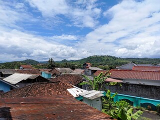 Obraz premium A charming residential district with colorful roofs and buildings against a backdrop of fluffy clouds, creating an idyllic scene.