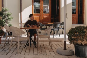Asian tourist man having a coffee in a cafe in tourist area in Albania.