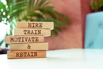 Wooden blocks with words 'Hire, Train, Motivate and Retain'.