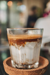 Close up dirty coffee in transparent glass served on black tray in the cafe.