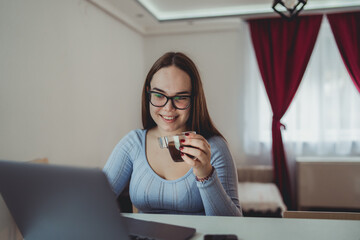 A young girl is studying or doing business from home on her laptop	
