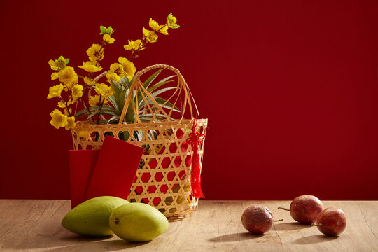 Some mangoes and passion fruits placed on table. A basket with apricot blossoms for Chinese new year holiday concept. Front view