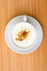 A Glass of cappucino coffee, sprinkled with coffee powder on top of the foam