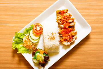 A Chicken Cutlet dish served weith rice and a side of salad, topped with rica rica chili