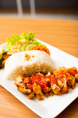 A Chicken Cutlet dish served weith rice and a side of salad, topped with rica rica chili
