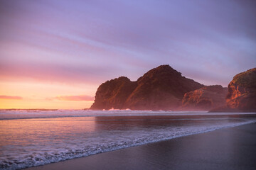 Purple skies and gentle waves at Bethells Beach, New Zealand.