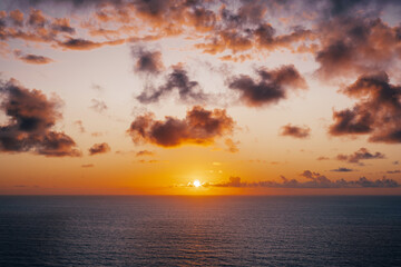 The infinite expanse of the ocean horizon at sunset, as vibrant pink, orange, and purple clouds fill the sky.