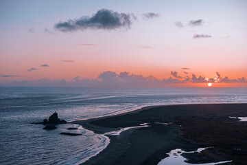 Whatipu beach at sunset, with vibrant purple clouds adding a touch of magic to the sky.