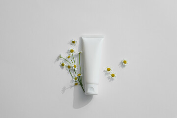 Top view of blank plastic cosmetics and matricaria chamomilla on white background. Space for product presentation. Advertising photo. Mockup