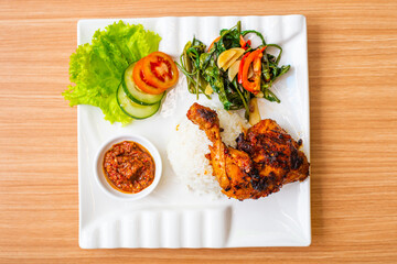 Grilled chicken thigh served with salad and a side of rice and home made chili