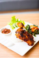Grilled chicken thigh served with salad and a side of rice and home made chili