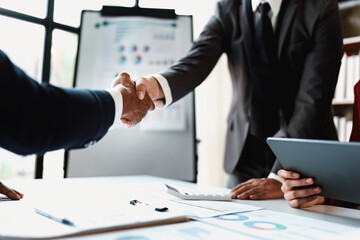 Asian entrepreneurs handshakes to congratulate the agreement between the two companies to enhance investment and financial strength. deal concept