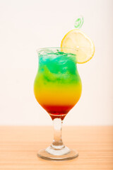 A Very colourful tropical drink served with a sliced lemon