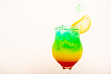 A Very colourful tropical drink served with a sliced lemon