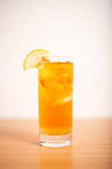 A glass of iced lemon tea served with a sliced lemon wedge
