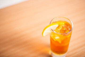 A glass of iced lemon tea served with a sliced lemon wedge