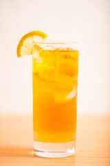 A glass of iced lemon tea served with a sliced lemon wedge