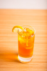 A glass of iced lemon tea served with a sliced lemon wedge