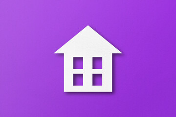 White paper cut out house shape isolated on purple paper background.
