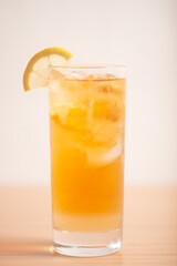 A glass of iced lemon tea served with a sliced lemon wedge