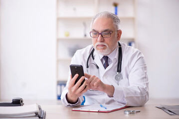 Old male doctor in telemedicine concept