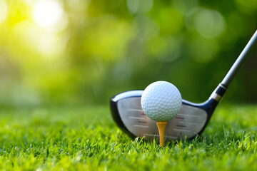 Front view of  golf ball on tee with golf drivers at golf course.