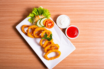 Deep fried onion rings served with tartar sauce and chili sauce