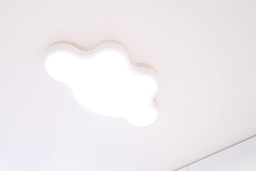 Ceiling lamp in the shape of a cloud on a white stretch ceiling