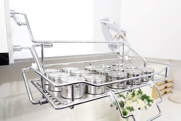 Fototapeta na wymiar Pull-out spice rack in chromed metal with many jars. Kitchen furniture