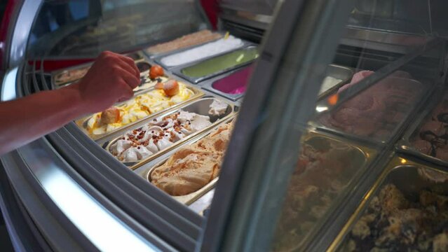 A hand chooses ice cream in an Italian gelato shop
