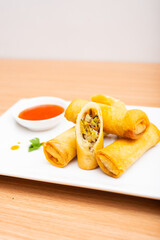 Fried spring rolls served with a side of chili sauce