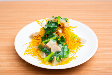 A plate of fried crispy noodles served with vegetables and sauce