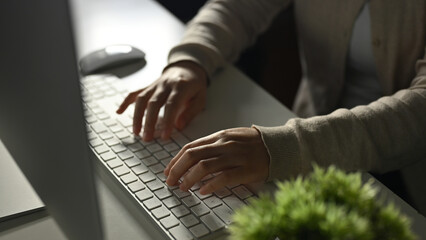 Close-up image of a female freelancer or office worker typing on computer keyboard