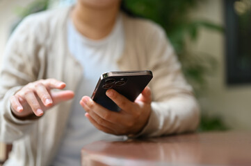 Cropped image of an Asian woman using her smartphone at outdoor table