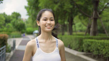 Portrait of Asian woman girl in yoga class club doing exercise, runing or jogging at public garden park. Outdoor sport and recreation. People lifestyle activity with nature trees view.