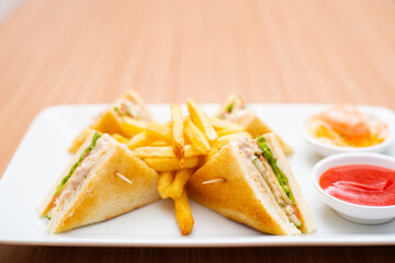 A Serving of club sandwich served with side of fries