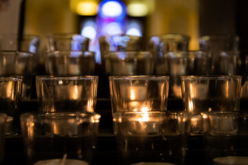 Atmospheric picture of lit candles at a prayer area inside a Catholic cathedral.