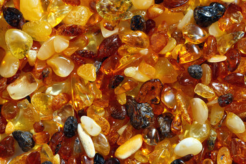 Natural gemstone amber texture background, small stones yellow orange gradient color. Natural mineral material for jewelry. Top view Amber texture. Aesthetic wallpaper, pieces ancient resin.