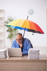 Old male employee holding an umbrella in the office