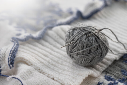 Knitting a winter sweater with patterns. Gray ball with a needle for stitching details.