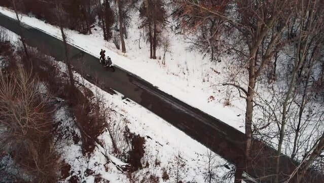 Driving Motorcycle On The Road Through Snow-covered Forest In Wasatch Range, Near Hobble Creek Canyon In Utah At Winter. aerial tilt-up