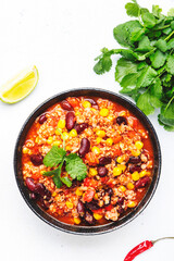 Chili con carne with beef, red beans, paprika, corn and hot peppers in tomato sauce, spicy tex-mex dish, white table background, top view