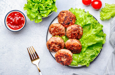 Homemade fried pork and beef meatballs with green lettuce and tomatoes, white table background, top view