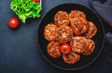 Homemade fried pork and beef meatballs in frying pan, dark table background, top view