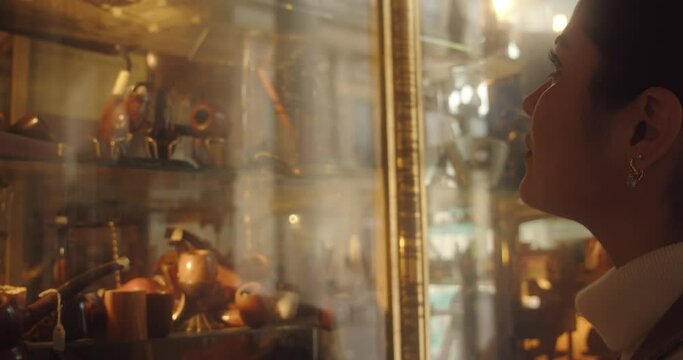 Brunette looks into shelves of antique store, close up side view