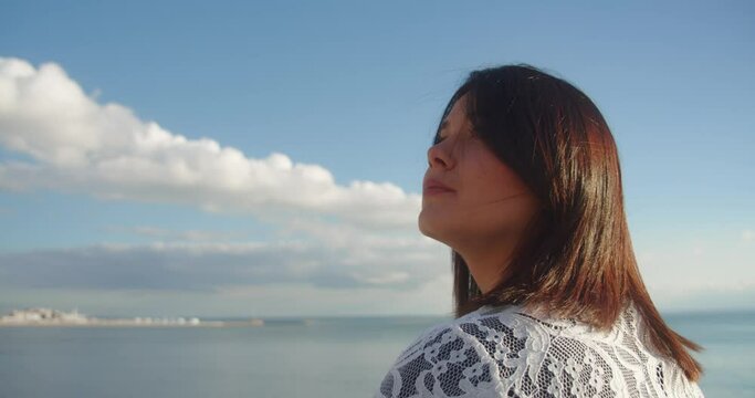 Attractive brunette enjoys coastal sunshine on French coastline, side view