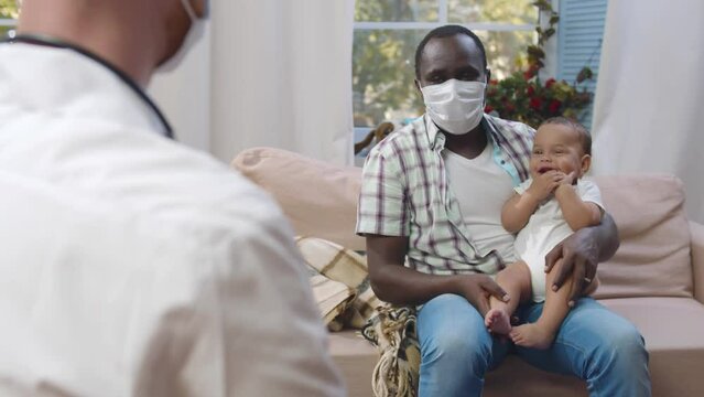 Doctor visit African-American father with dick infant baby at home. Realtime