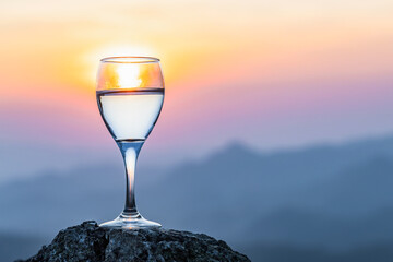 Glass of champagne on top rock mountain sunset view background